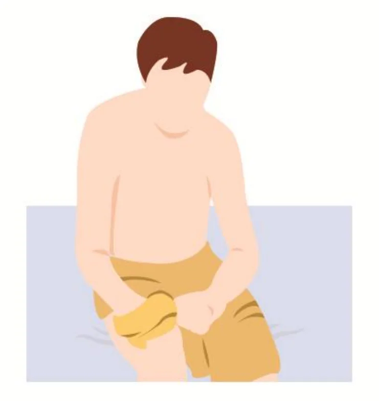 침대에 앉아 강한 손으로 약한 쪽 손목에 옷소매를 끼우는 모습